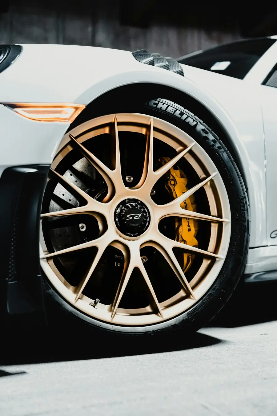 Close-up of a Porsche 911 GT3 RS front wheel with gold spokes, yellow ceramic brake calipers, and Michelin tire